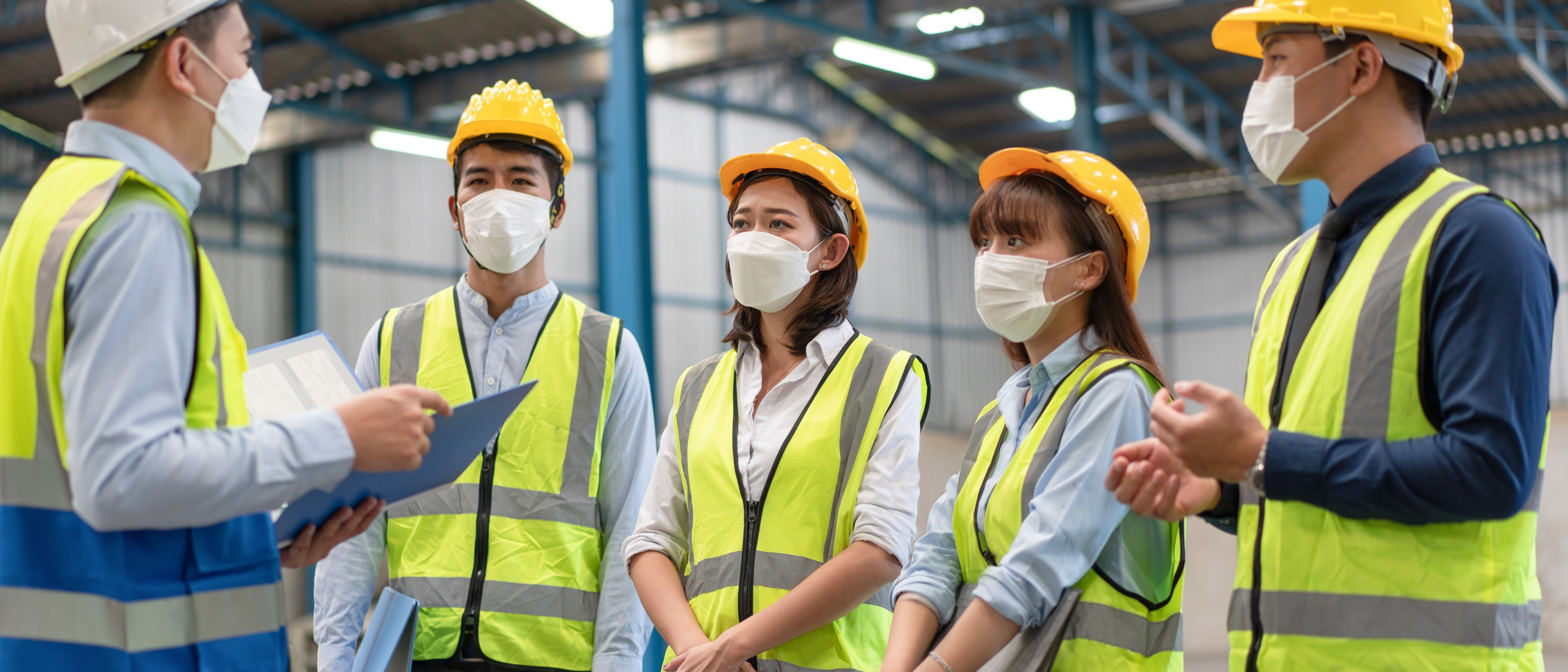 5 individual wearing PPE indoors in a discussion
